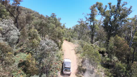 Aerial-Drone-Shot-of-4WD-Driving-up-Dirt-Road-Emerging-to-show-Blue-Water-and-Mountains-near-Lake-Eildon,-Victoria-Australia