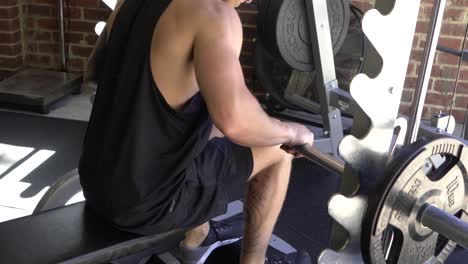 Muscly-man-in-home-gym-exercising-smith-machine-calf-raises-while-seated