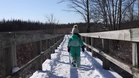 Little-girl-walking-down-winter-nature-path-slomo-zoomed-follow