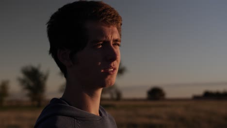 A-teenage-boy-with-a-sun-lit-face-watched-the-sun-setting-on-a-Kansas-farm-in-the-USA