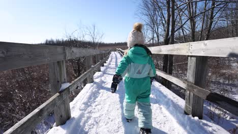Little-girl-walking-on-winter-nature-path-slomo-wide-angle-follow