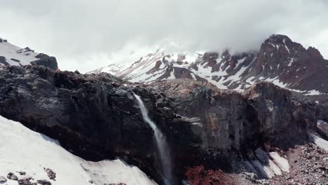 Incredible-aerial-panoramic-view-of-mountain-cliff-with-a-waterfall-from-melted-snow