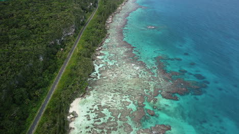 Aerial-pull-back-shot-revealing-breathtaking-coastline,-crystal-water-and-tropical-forest