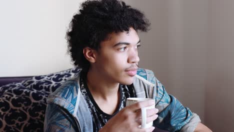A-mix-race-teen-boy-drinks-from-a-mug,-close-up