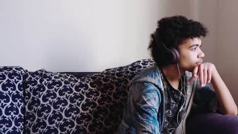 A-mix-race-teen-boy-listens-to-music-on-headphones,-medium-shot