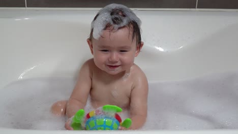 Süßes-Ukrainisch-koreanisches-Kleinkind,-Das-Mit-Bunter-Spielzeugschildkröte-In-Der-Badewanne-Mit-Schaum-Spielt