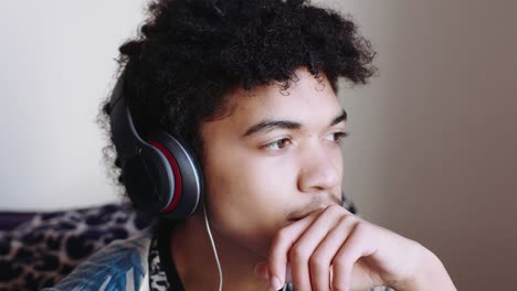 A-mix-race-teen-boy-listens-to-music-on-headphones,-close-up