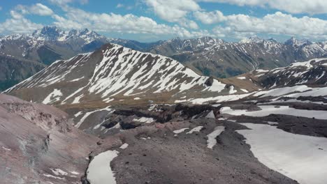 Aerial-panoramic-view-of-stunning-continuous-mountain-range-partially-covered-with-snow