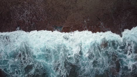 Rising-bird's-eye-view-of-ocean-waves-crashing-against-Maré-Island-coast