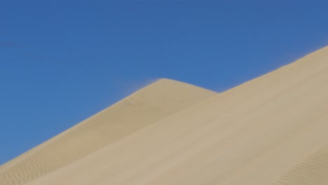 Telephoto-shot-of-sand-blowing-off-the-top-of-Giant-Te-Paki-Sand-Dunes-in-Cape-Reinga,-Northland,-New-Zealand