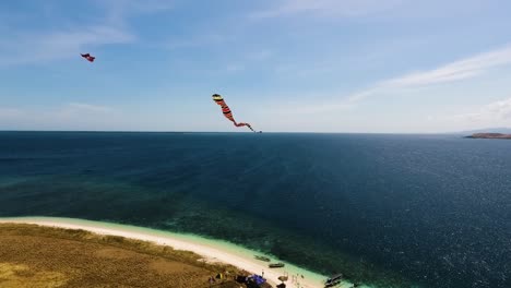 Drone-close-up-to-kite-flying-over-a-tropical-island-with-white-sand-lonely-beach-in-Kenawa-Island,-Sumbawa,-Indonesia,-beautiful-wild-nature-landscape-archipelago