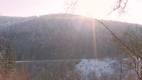 Sonne-Scheint-Auf-Einem-Eisenbahnviadukt-über-Ein-Bergtal,-Fallender-Schnee