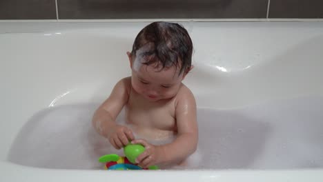 Cheerful-Toddler-Happily-Playing-With-Plastic-Toy-While-Bathing-In-The-Bathtub