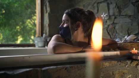 Young-attractive-female-having-a-fancy-bath-in-a-jacuzzi-with-covid-mask-hope-with-big-green-nature-window-able-to-slow-motion-60fps