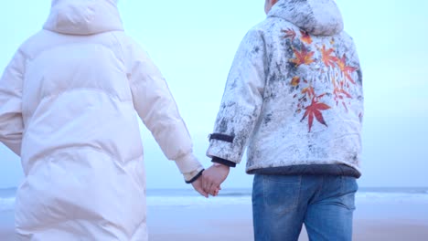 Lovers-walking-hand-in-hand-on-the-beach，Romantic-couple-walking-on-the-beach