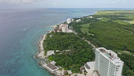 Cozumel-Mexico-Aerial-v21-establishing-shot-drone-flying-along-the-island-shoreline-over-beachfront-holiday-hotels,-resorts-and-golf-course-with-beautiful-seascape---September-2020