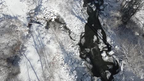 Luftaufnahmen,-Die-Entlang-Des-Eagle-River-Fliegen,-Mit-Frischem-Schnee-Auf-Dem-Boden-Und-Felsen-Und-Bäumen,-Die-Das-Ufer-Säumen