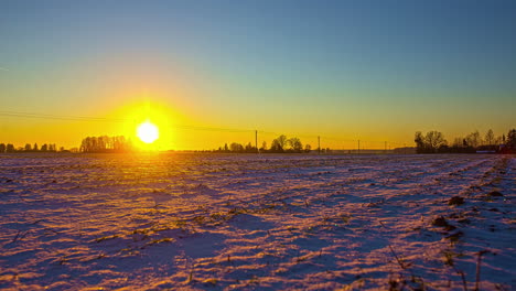 Aerial-drone-footage-of-a-snow-covered-farmers-field-in-winter-with-sunset-timelapse