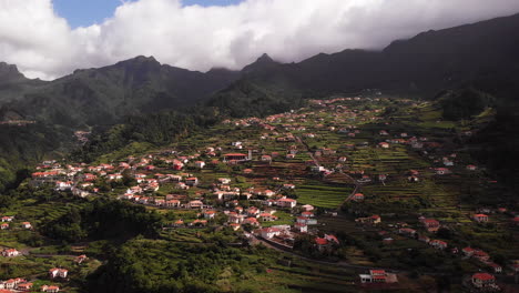Aerial-view-of-a-town-in-a-mountain-valley-on-a-green-escarpment-hill-in-Sao-Vicente,-Madeira