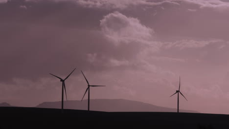Silhouetted-turning-wind-turbines-against-a-cloudy-and-moody-sky