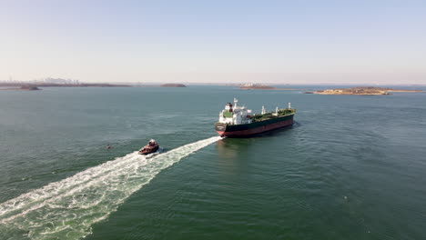 Aerial-static-shot-of-a-Tanker-on-Boston-Harbor,-with-tugboat-following
