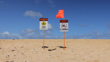 Orange-Flag-Waving-In-The-Wind-At-NO-SWIMMING-With-STRONG-CURRENT-Warning-Sign-At-The-Beach-In-Hawaii