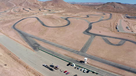 Cars-race-around-a-giant-racetrack-in-the-Mojave-Desert---aerial-view-in-slow-motion