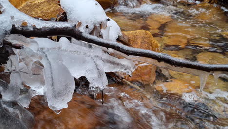 Gefrorene,-Mit-Eis-Und-Eiszapfen-Bedeckte-Äste-Fielen-Im-Winter-über-Einen-Kleinen-Waldfluss