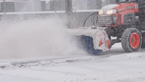 Municipal-service-worker-operating-snow-clearing-truck-with-broom,-removing-snow-from-street-during-blizzard-snow-storm