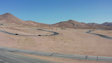 Autos-Fahren-Um-Die-Meisterschaft-Auf-Einer-Rennstrecke-Mit-Der-Mojave-Wüstenlandschaft-Als-Hintergrund---Luftaufnahme