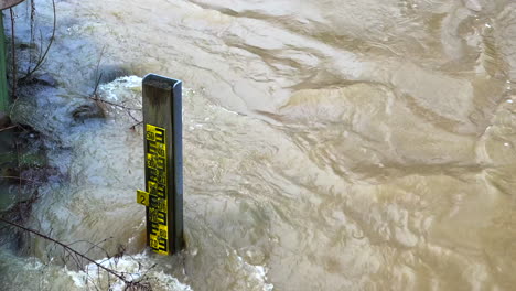 At-a-water-level-meter-standing-in-the-river,-you-can-read-the-water-level-at-high-water-in-slow-motion