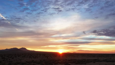 Amanecer-Dorado-Sobre-El-árido-Paisaje-Del-Desierto-De-Mojave-Con-Nubes-Coloridas-Sobre-Su-Cabeza