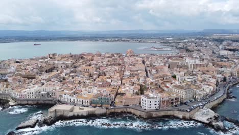 The-beautiful-ortigia-of-siracusa-in-sicily-,-drone-pans-the-view-towards-below-to-the-crystal-blue-turquoise-sea