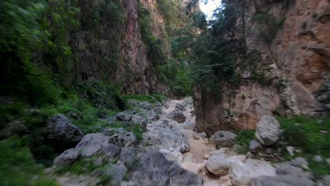 Fly-over-rocks-between-steep-cliffs,-Gjipe-canyon,-Albania