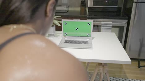 A-static-shot-of-a-black-female-getting-a-work-out-in-in-front-of-her-green-screen-computer-lap-top