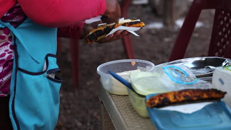 Female-Vendor-Preparing-Grilled-Banana-Street-Food-For-Customer-In-San-Cristobel-In-The-Galapagos