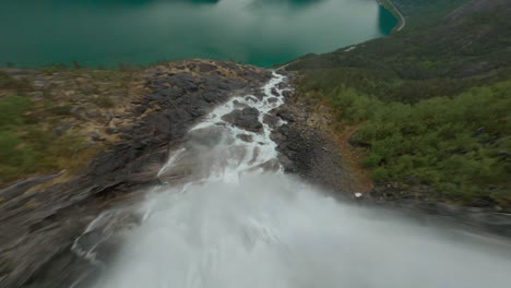 Aerial-fpv-flight-downhill-Langfoss-Waterfall-flowing-into-idyllic-lake-of-Norway