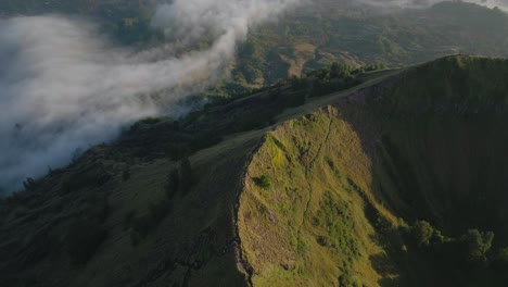 Mount-Batur-ridge-with-hiking-trail-visible-during-sunrise,-aerial