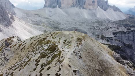 A-hiker-is-standing-on-a-hill-top-with-a-view-over-Tre-Cime-di-Lavaredo-in-the-Dolomites-of-North-Italy