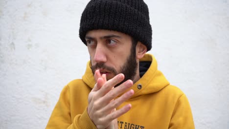 Man-In-Hipster-Beanie-Hat-And-Yellow-Hoodie-Jacket-Rubbing-Hand-Palms-And-Freezing-In-Cold