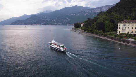 Ferry-Boat-Traveling-on-Lake-Como-Water-Surface-with-Beautiful-Alps-Background,-Aerial