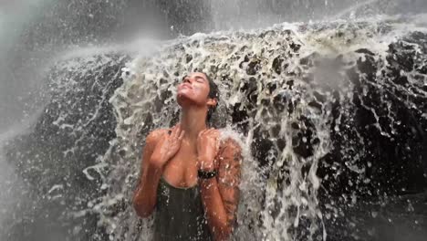 A-beautiful-young-Brazilian-woman-in-a-swimsuit-smiling-and-looking-up-and-enjoying-swimming-under-the-Mosquito-waterfall-in-Chapada-Diamantina-in-Northeastern-Brazil-in-the-state-of-Bahia-on-vacation