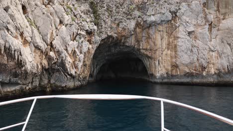 Barco-Acercándose-A-La-Cueva-Del-Acantilado-Del-Océano-En-La-Costa-De-La-Isla-De-Capri,-Italia