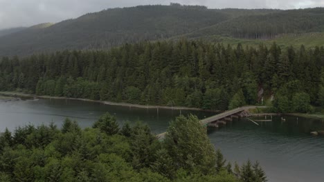 Drone-flying-towards-the-bridge-in-Port-Renfrew,-British-Columbia,-on-a-cloudy-day