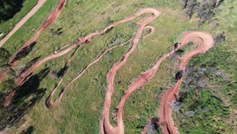 Mountain-bike-trail-with-rider-riding-down,-drone-top-down-shot