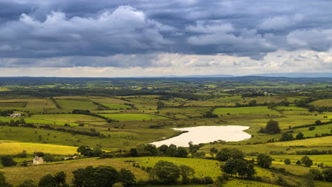 Time-lapse-of-rural-farming-landscape-with-grass-fields,-lake-and-hills-during-a-cloudy-day-in-Ireland