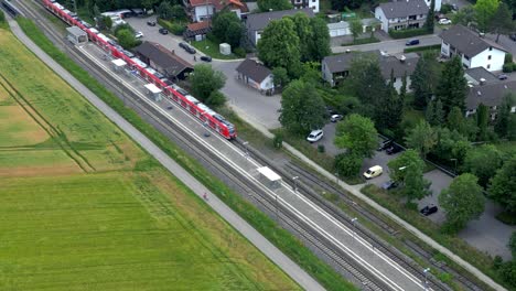Drone-tracks-commuter-train-on-rural-stop-near-Munich