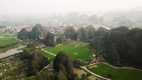 Circling-above-the-misty-limestone-karsts-of-Tam-Coc-surrounded-by-rural-farms