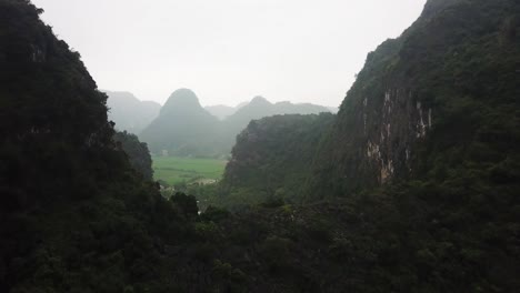 Ascending-from-behind-two-Karsts-to-reveal-a-lush-green-mountainous-valley-of-Tam-Coc