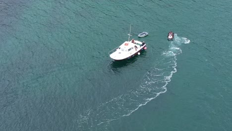 Aerial-orbit-shot-of-a-jet-ski-and-small-boat-on-the-Cornish-coast,-UK